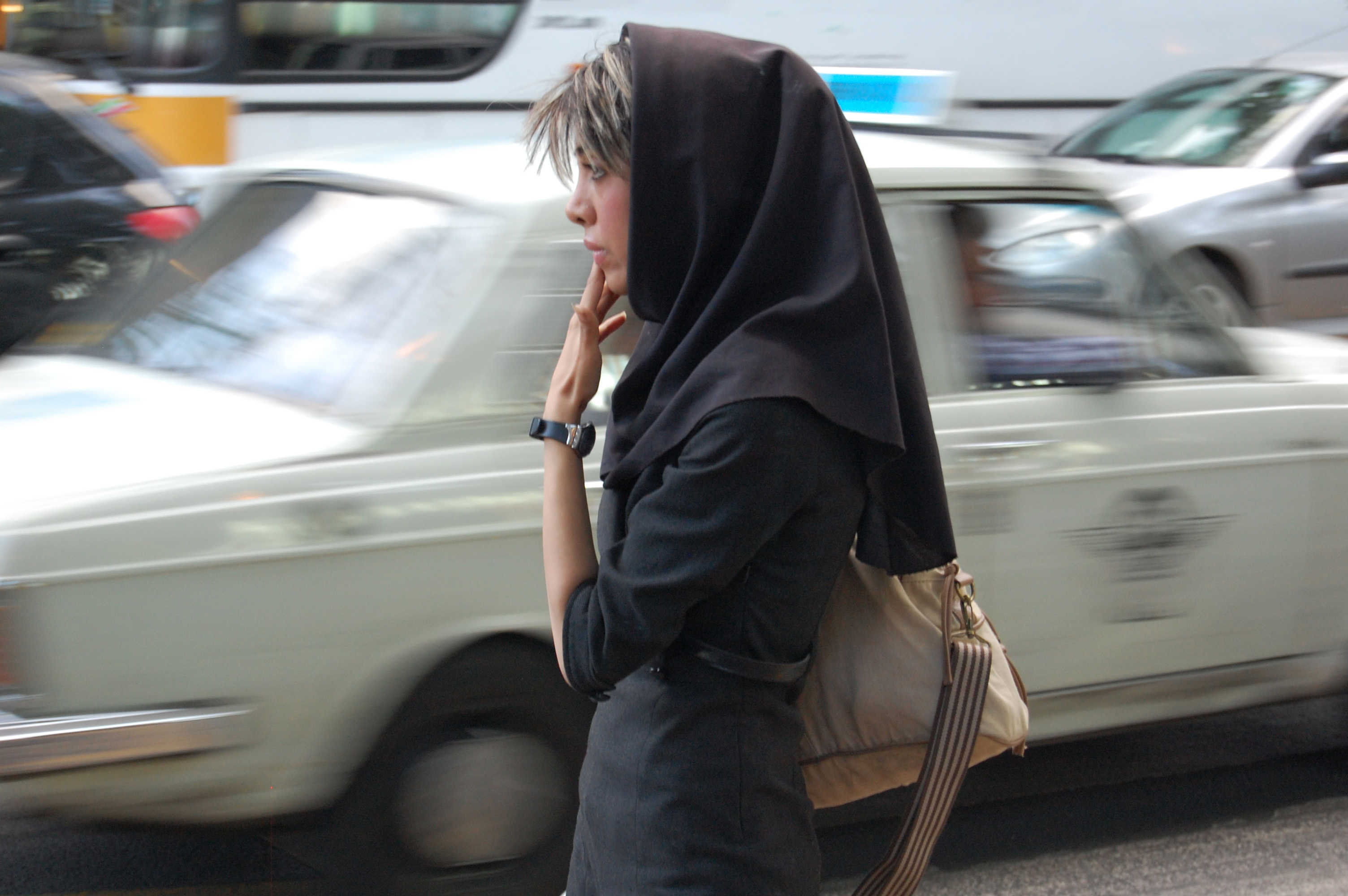 Iranian woman with traffic whizzing by.